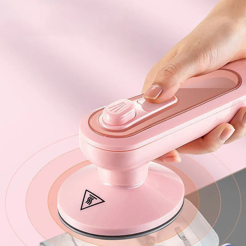 Pink portable electric iron with EU and US plug adapters on a white background