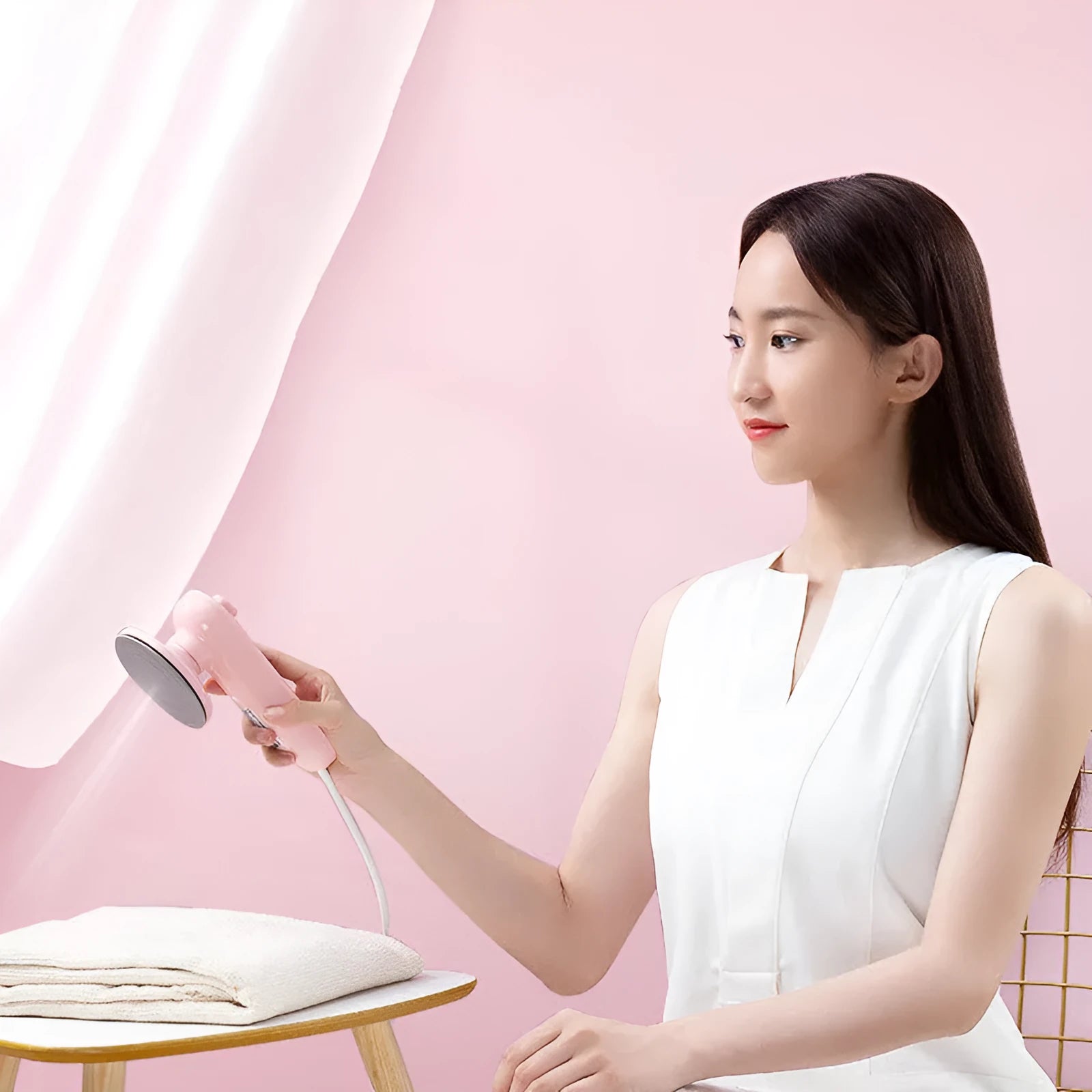 Pink portable electric iron with EU and US plug adapters on a white background