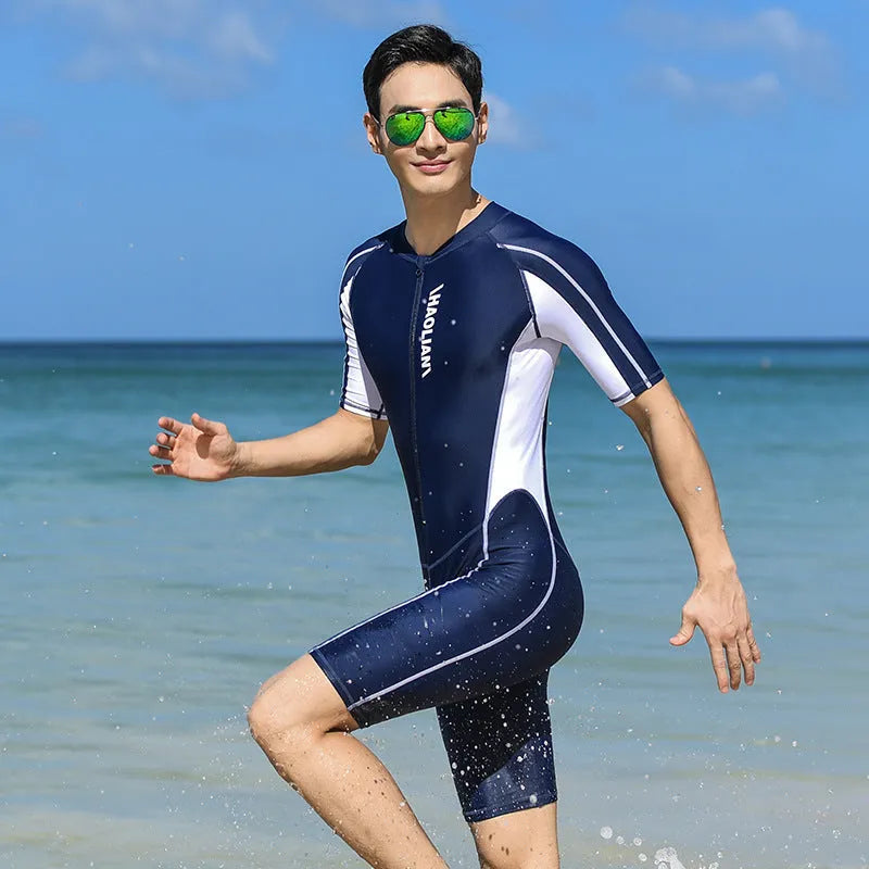 Men's short-sleeved neoprene surfing suit with front zip, in black, shown on a model.