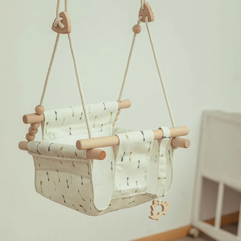 Cotton canvas baby swing chair with wooden seat and cushion hanging indoors