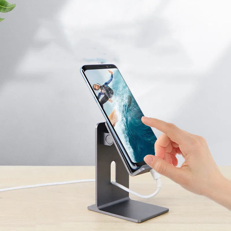 Dark space grey alloy mobile phone and tablet holder on a wooden desktop.