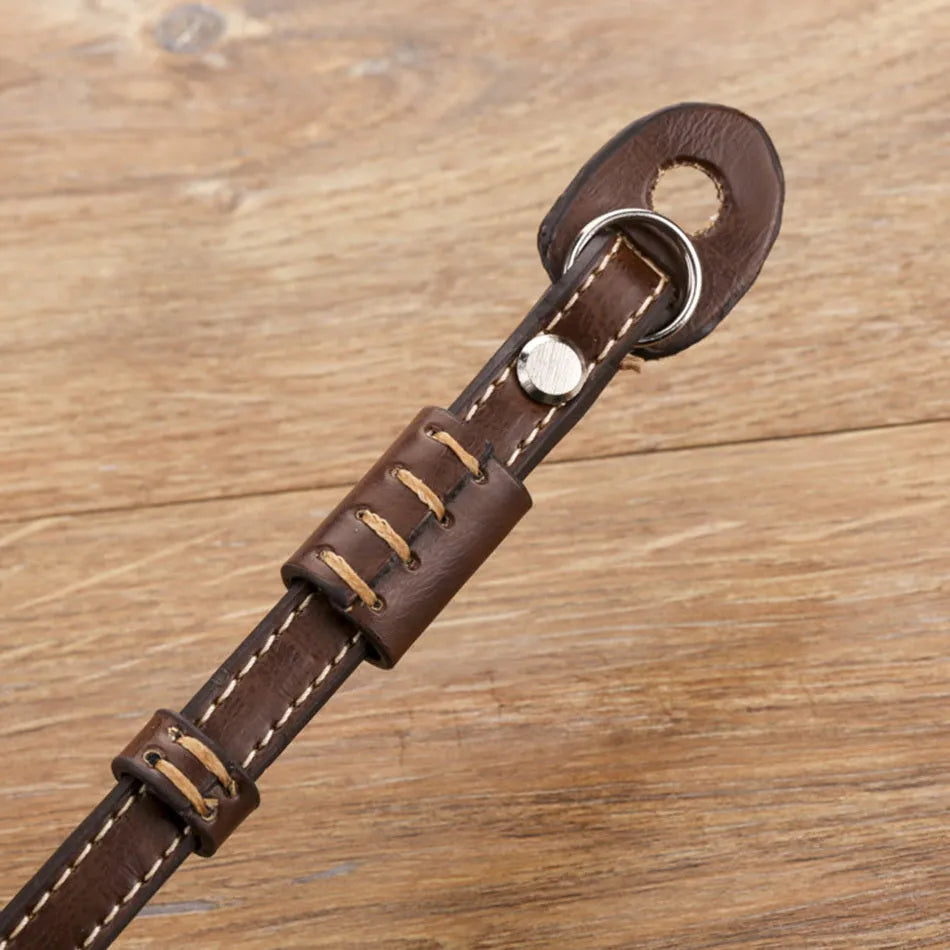 Black camera wrist strap with metal quick-release buckle shown attached to digital camera