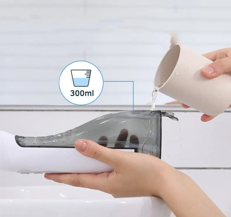 White portable oral irrigator with large 330ml water tank and multiple nozzles on a bathroom counter