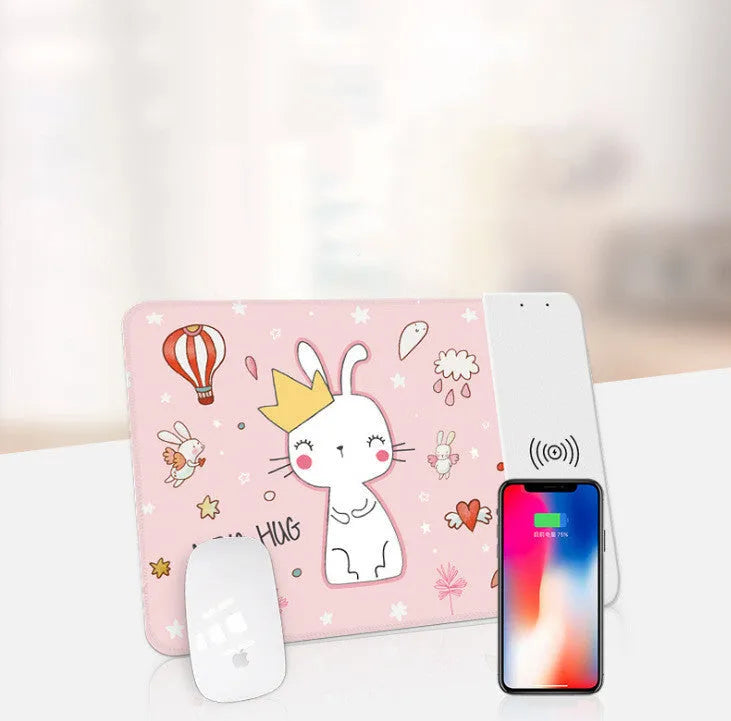 Black wireless charging mouse pad with RGB lighting edge and a cartoon design, shown on a desk.