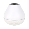 White round Bluetooth humidifier and aroma diffuser with night light on a table.