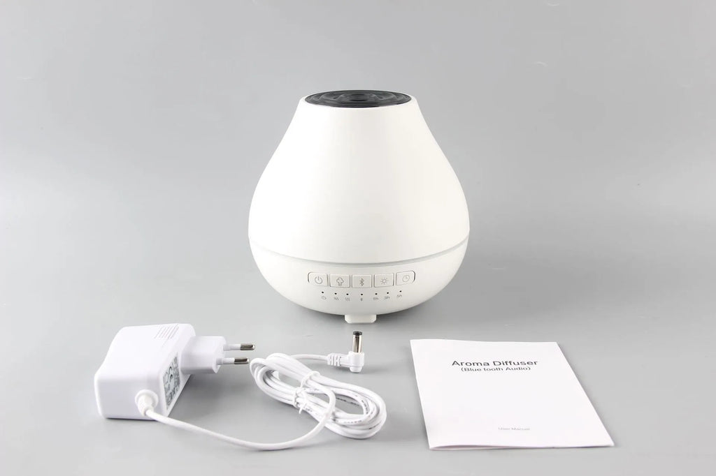 White round Bluetooth humidifier and aroma diffuser with night light on a table.
