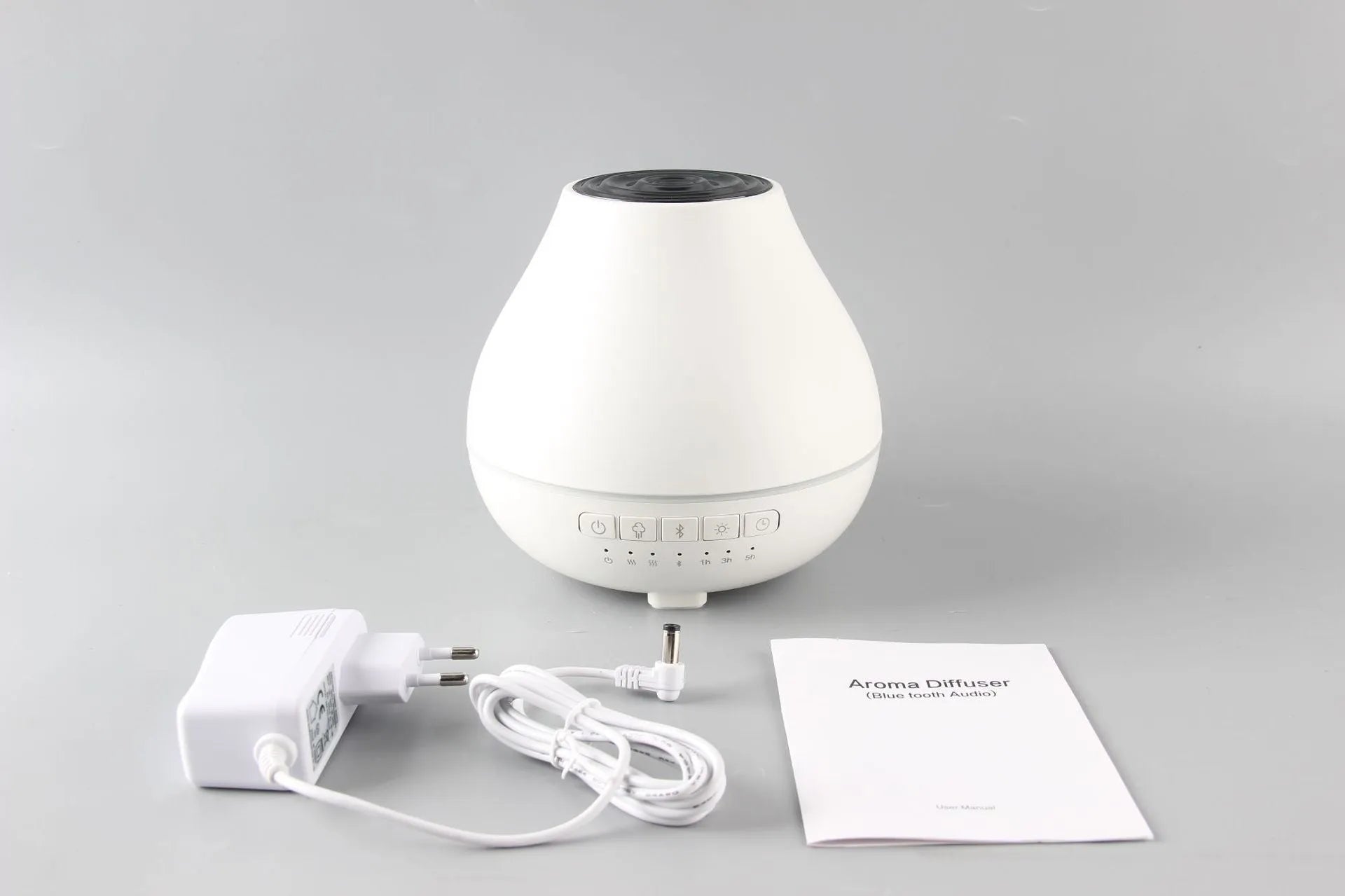 White round Bluetooth humidifier and aroma diffuser with night light on a table.