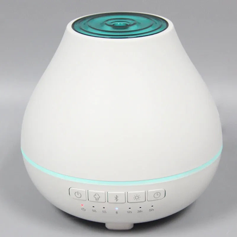 White round Bluetooth humidifier and aroma diffuser with night light on a table.