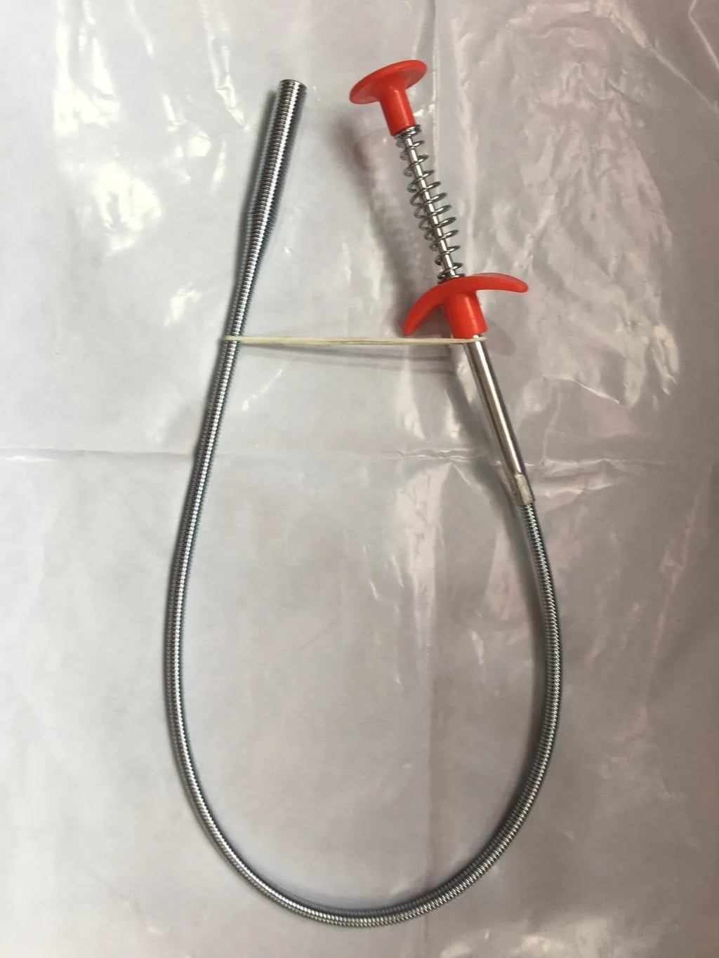 Black sewer dredge spring drain unclogging tool with PP handle next to a kitchen sink