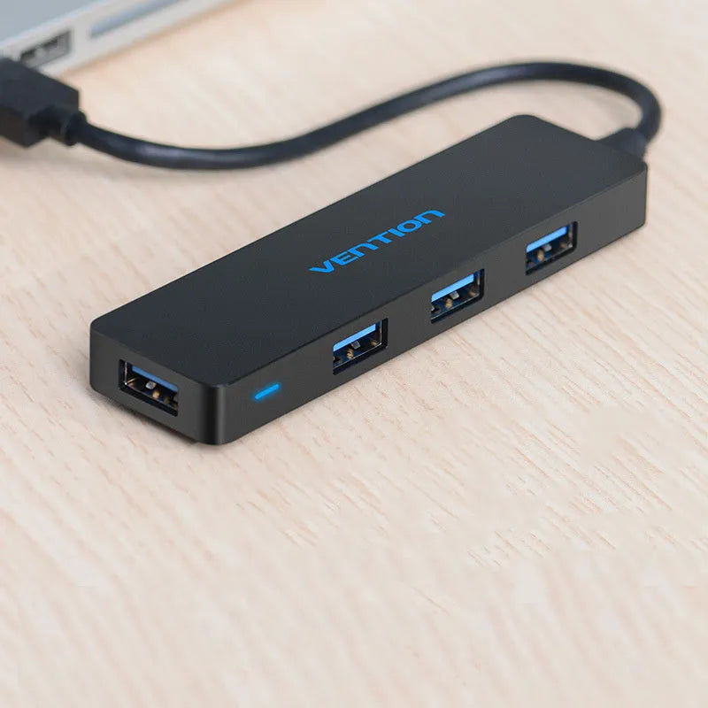 Black four-port USB 3.0 hub with a short 15cm cable on a desk