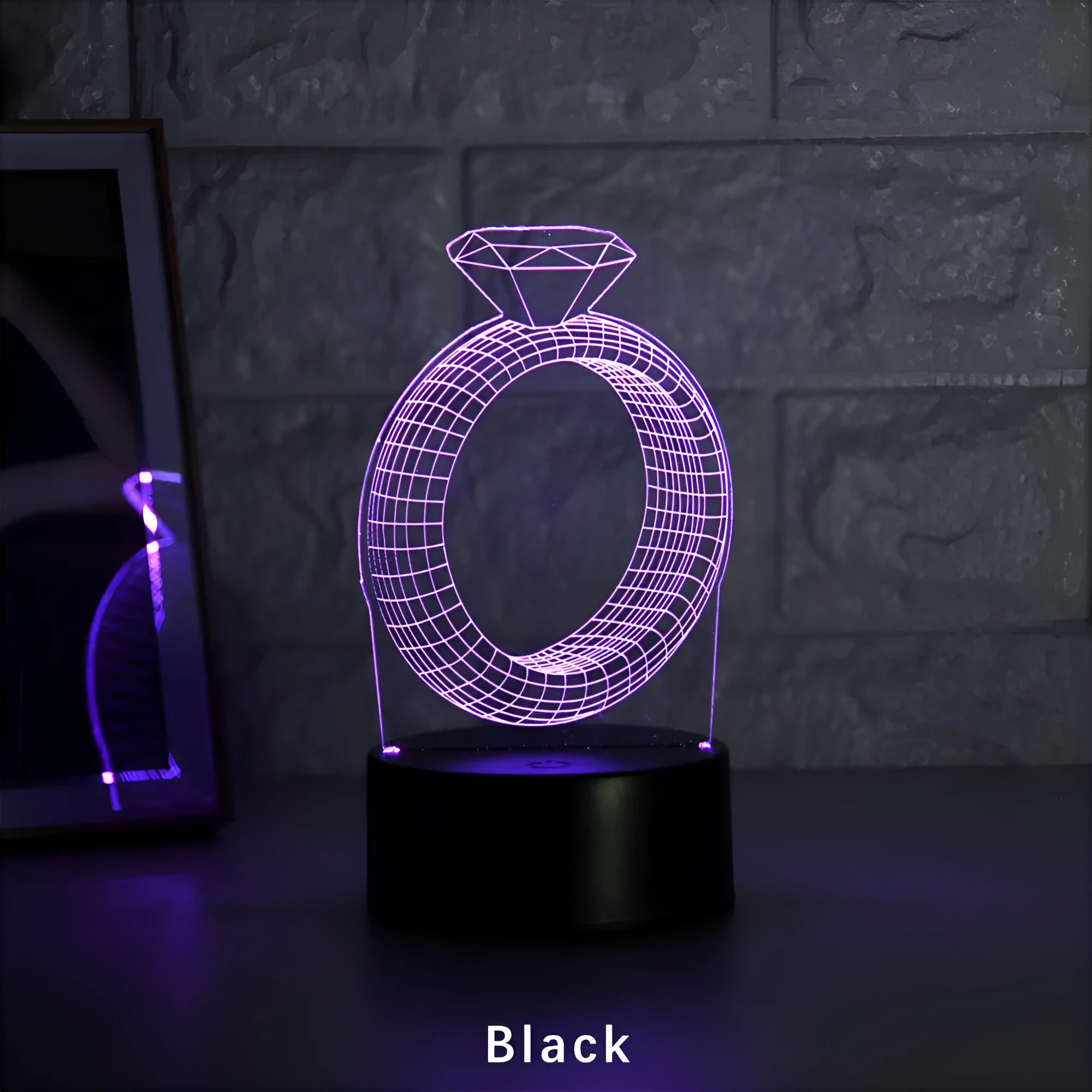 3D holographic diamond ring LED night light with colour changing modes on a bedside table.