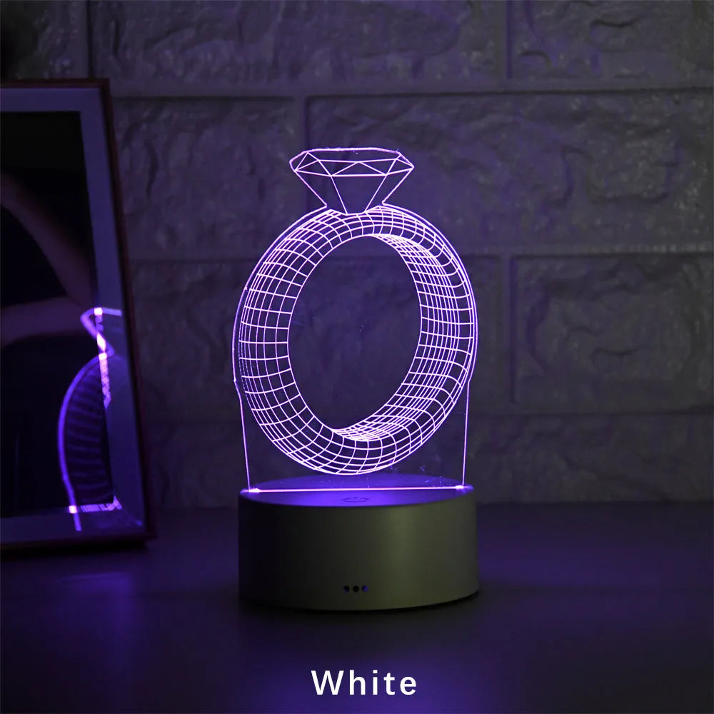 3D holographic diamond ring LED night light with colour changing modes on a bedside table.