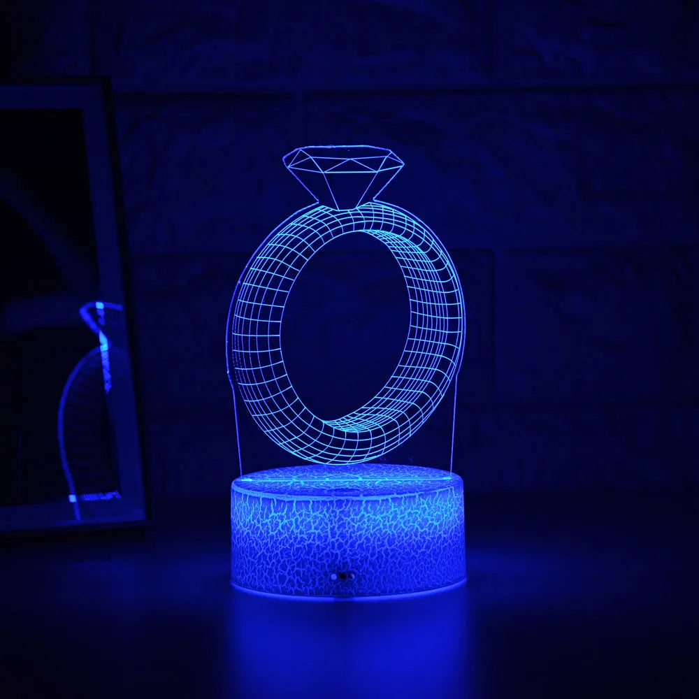 3D holographic diamond ring LED night light with colour changing modes on a bedside table.