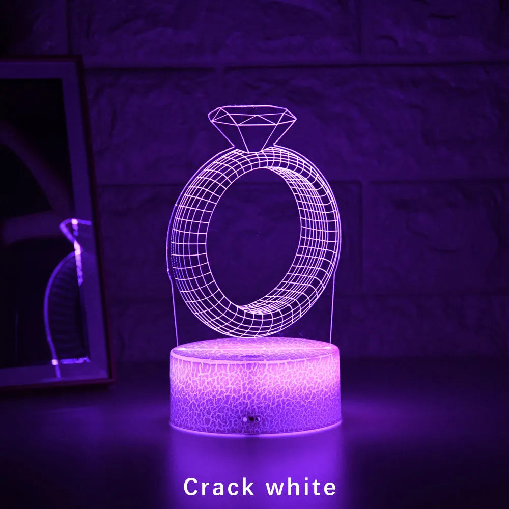 3D holographic diamond ring LED night light with colour changing modes on a bedside table.