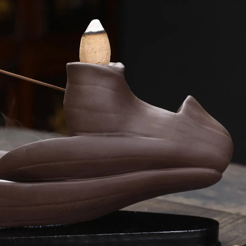 Brown purple sand backflow incense burner 8.5x21x9 cm on a wooden surface with smoke flowing downwards