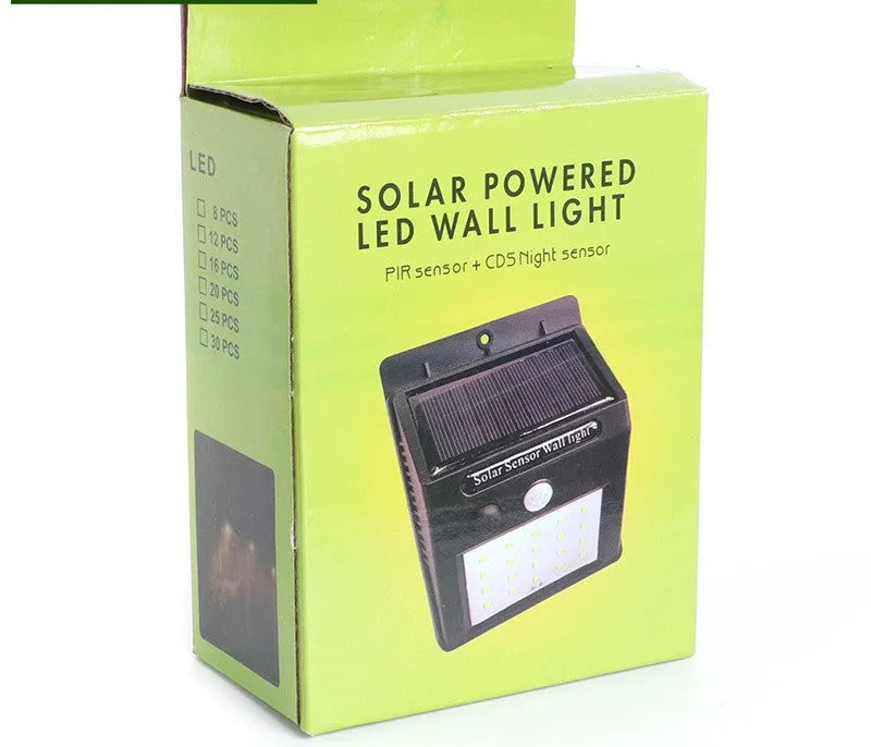 A white solar-powered garden lamp with LED lights and a solar panel on top, standing in a garden.