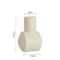 A simple hammer-textured ceramic vase in a Morandi colour on a wooden surface.