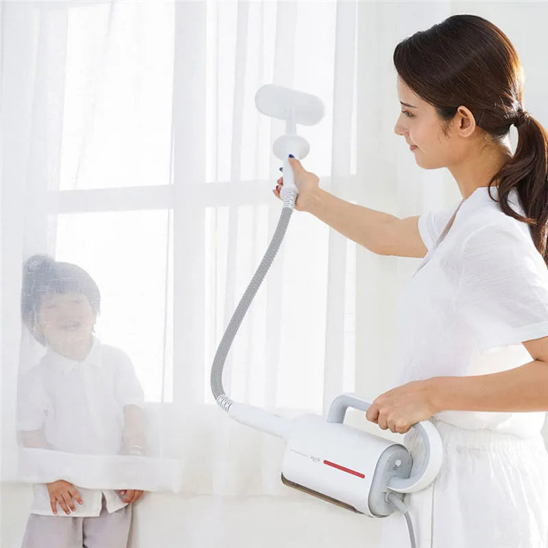Deerma DEM-ZQ610 white steam cleaner with brush heads and glass scraper on a grey surface