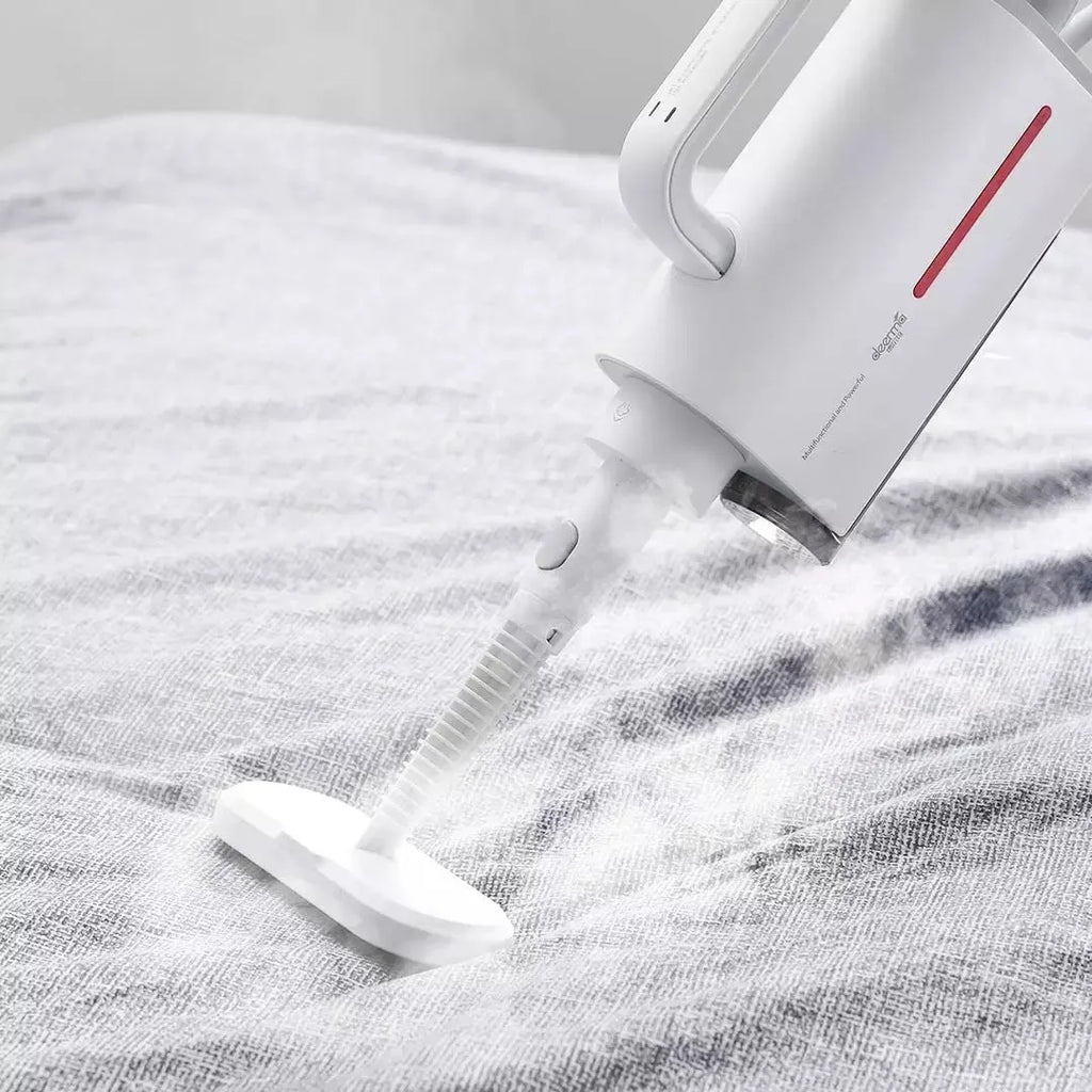 Deerma DEM-ZQ610 white steam cleaner with brush heads and glass scraper on a grey surface
