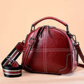 Round women's leather handbag with soft handles and a zip, shown in a choice of colours.