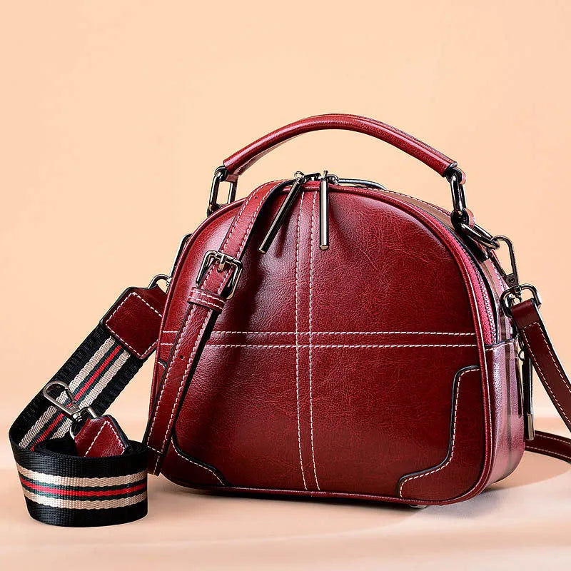 Round women's leather handbag with soft handles and a zip, shown in a choice of colours.