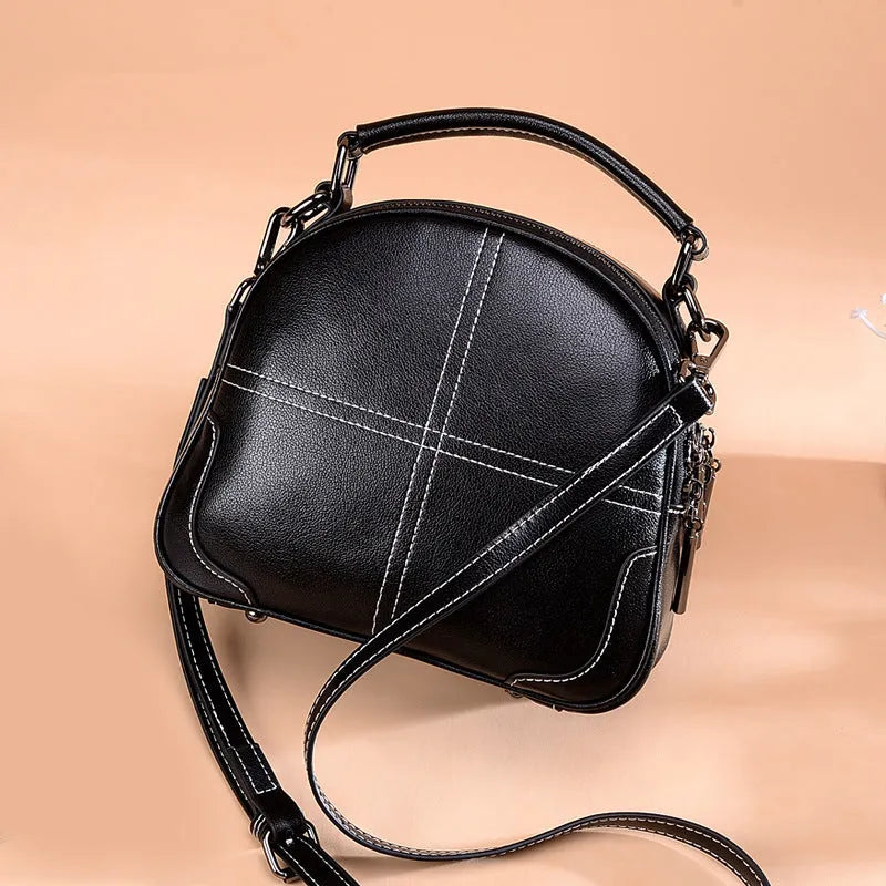 Round women's leather handbag with soft handles and a zip, shown in a choice of colours.