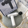 Black handheld fascia gun muscle massager on a grey background