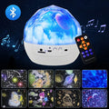 Compact white starry sky projector lamp with film discs on a table, projecting galaxy scene on wall.