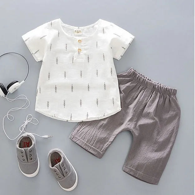 Baby boy wearing a blue crocodile print cotton t-shirt and matching blue shorts summer outfit set.