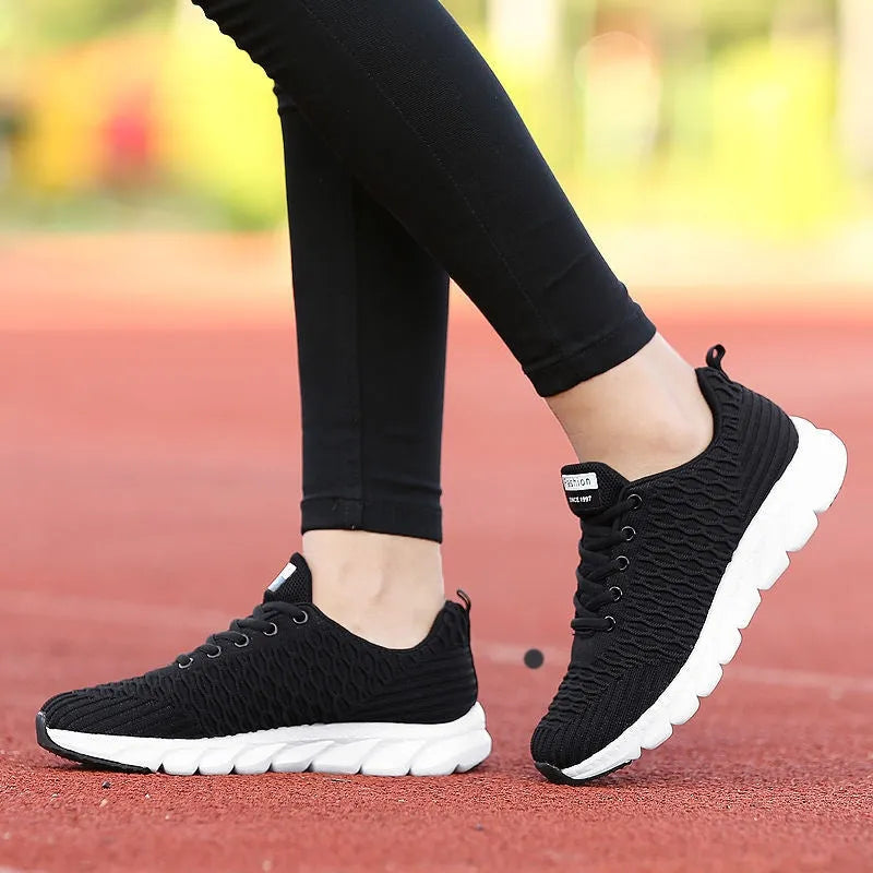 Women's running shoes in black with detailed view of fly weaving upper material and wear-resistant rubber outsole.