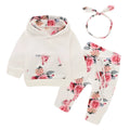 White cotton hooded pantsuit for a baby girl on a hanger, showing long sleeves and full-length trousers.
