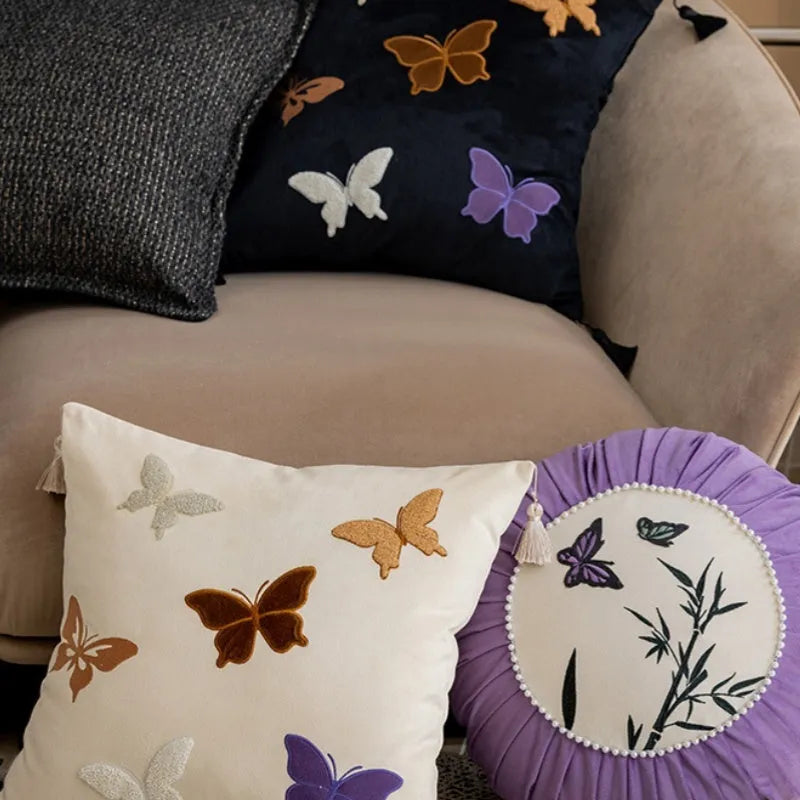 Square beige cushion with embroidered Chinese-style butterfly design.
