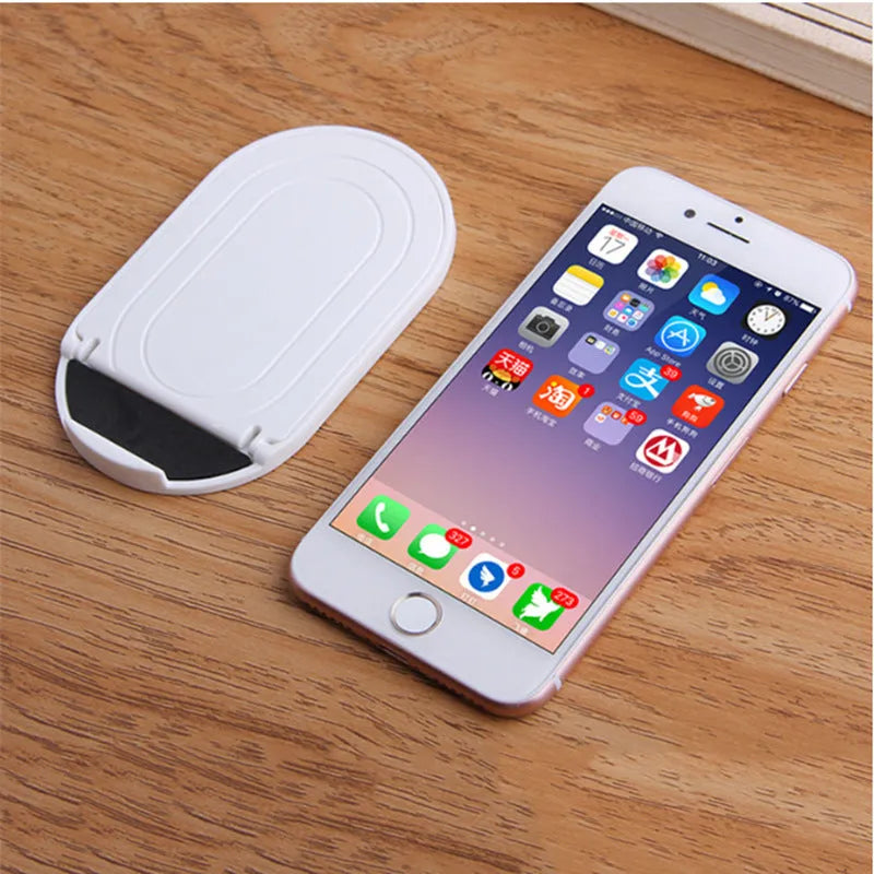 A foldable plastic mobile phone stand in a lazy bracket shape, shown in a selection of colours.