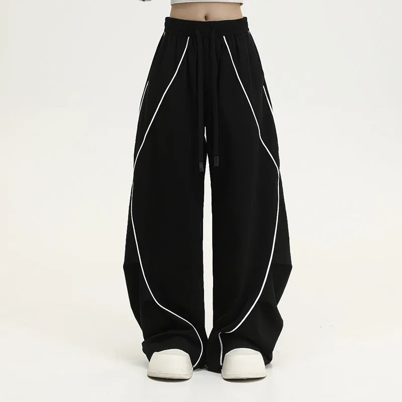 Black striped pleated wide-leg hip hop trousers laid flat, showing loose fit and mid waist.