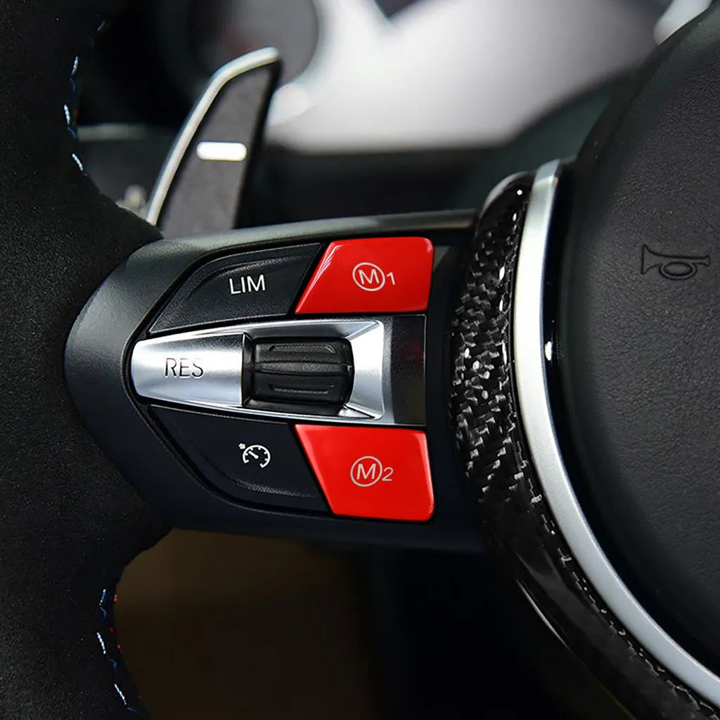 Pair of red and blue BMW M1 M2 steering wheel mode buttons on a dark background.