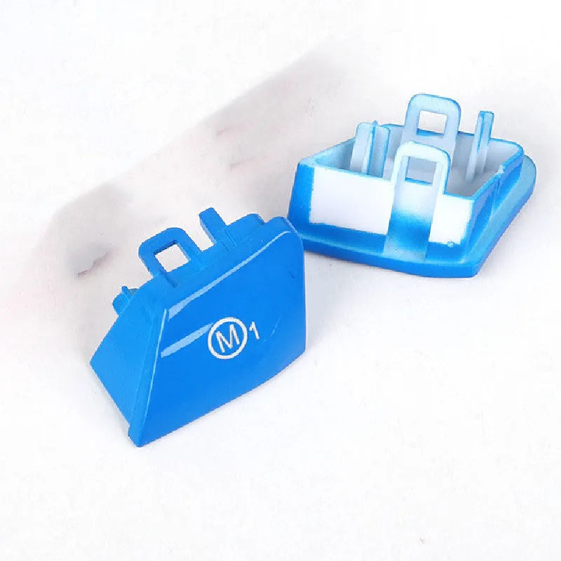 Pair of red and blue BMW M1 M2 steering wheel mode buttons on a dark background.