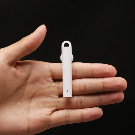 Compact black and white wireless Bluetooth headset showing size scale.