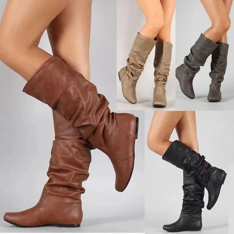 Women's black slip-on flat boots with round toe and high cylinder shaft on a non-slip rubber sole.