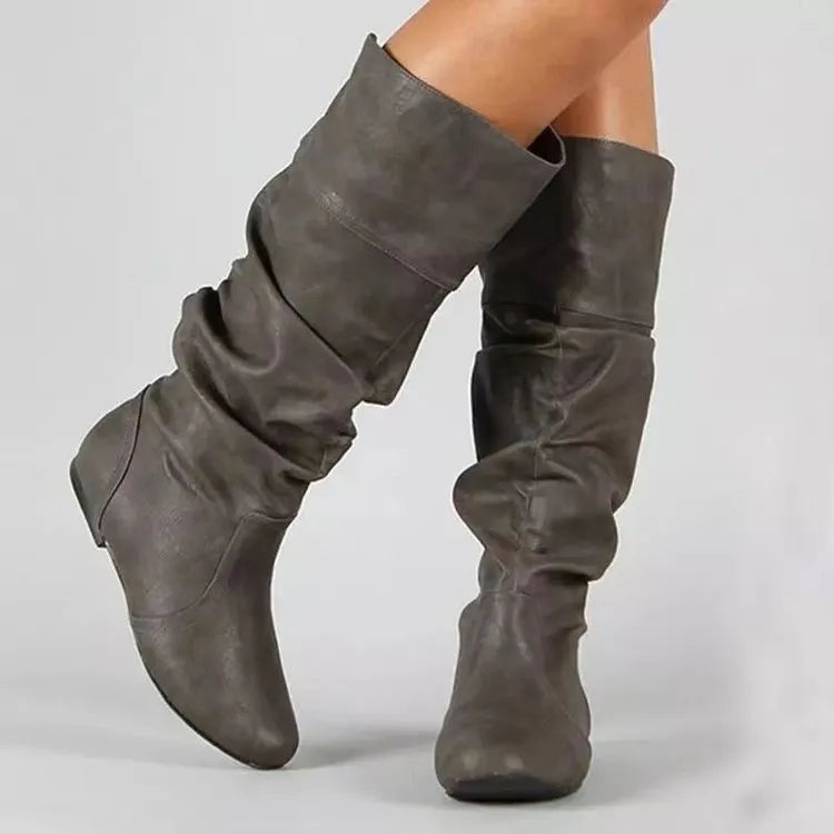 Women's black slip-on flat boots with round toe and high cylinder shaft on a non-slip rubber sole.