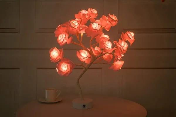 White and red rose flower shaped USB battery LED table lamp with warm white light on a table.