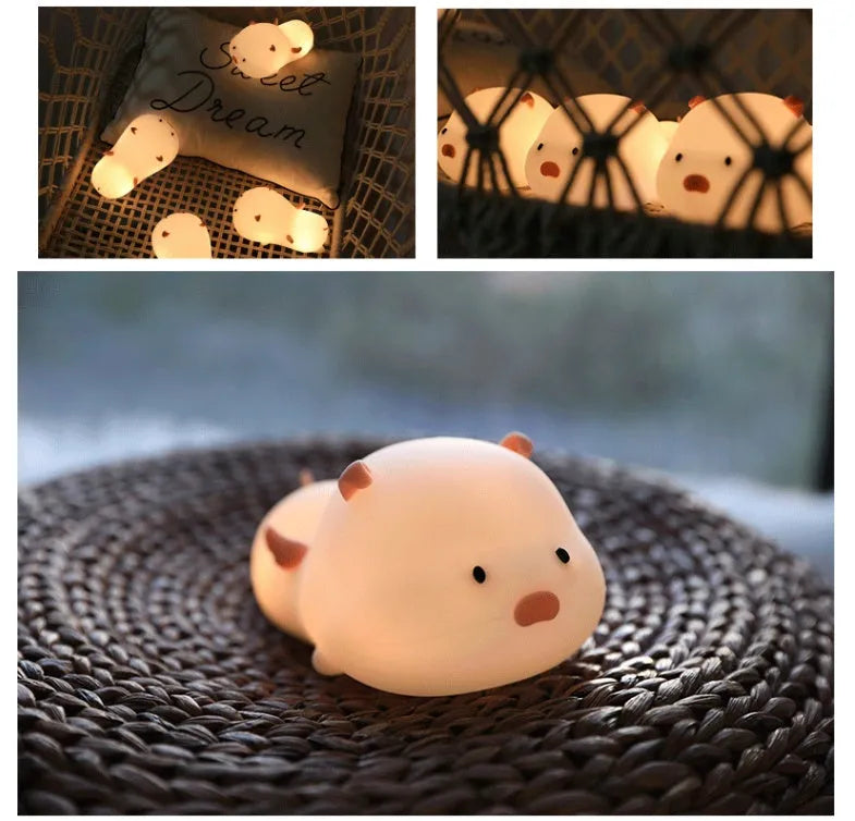 Blue silicone pig-shaped rechargeable LED night light with touch control on a wooden surface.
