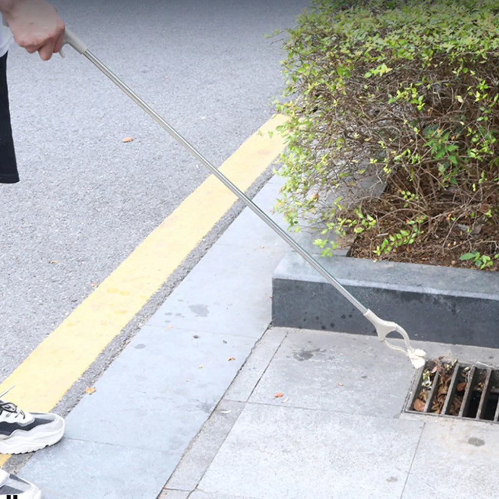 Stainless steel and plastic extended garbage picker tool with push handle and gripper jaws.