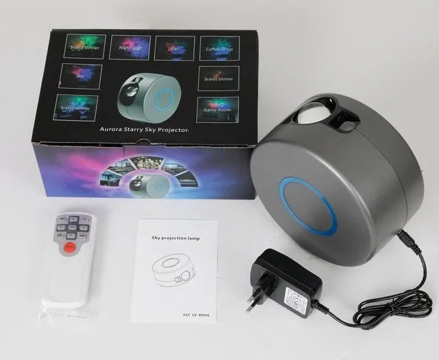 Grey starry sky projection lamp with remote control on a table, projecting colourful light dots on a dark wall.