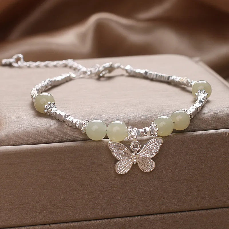 Hetian jade beads bracelet with silver butterfly pendant on a white background