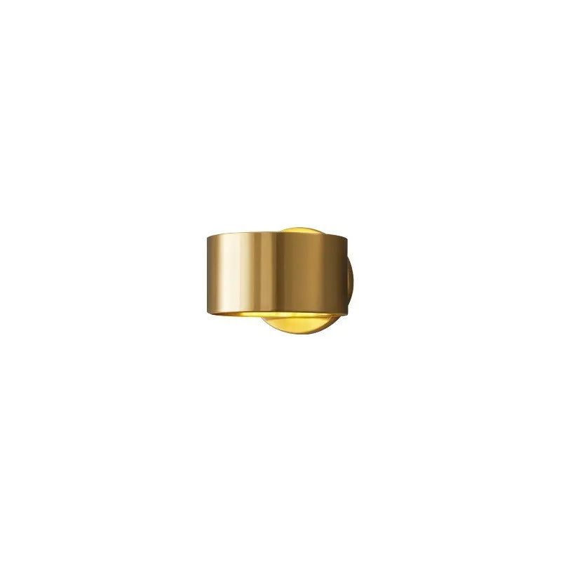 A modern simple style copper wall lamp in a gold finish, mounted on a wall.