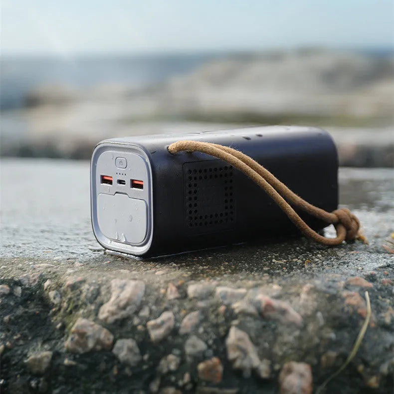 Black portable power bank with solar panel, showing size scale and output ports.