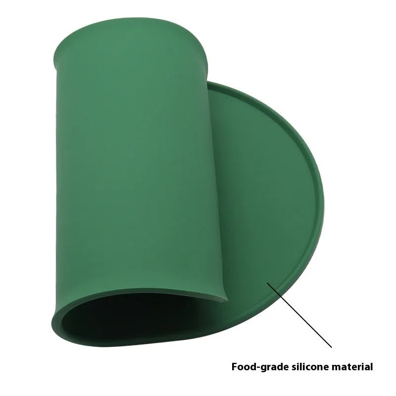 Silicone waterproof cat feeding placemat in beige colour on a floor next to a food bowl.