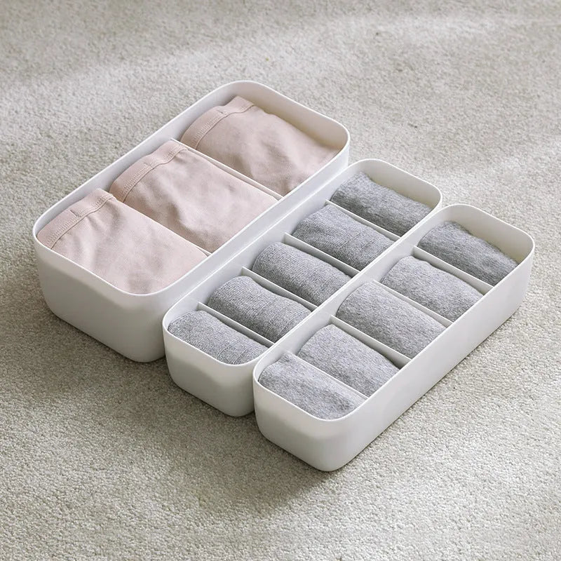 PP plastic socks and underwear storage box with grid compartments in apricot colour on a desktop