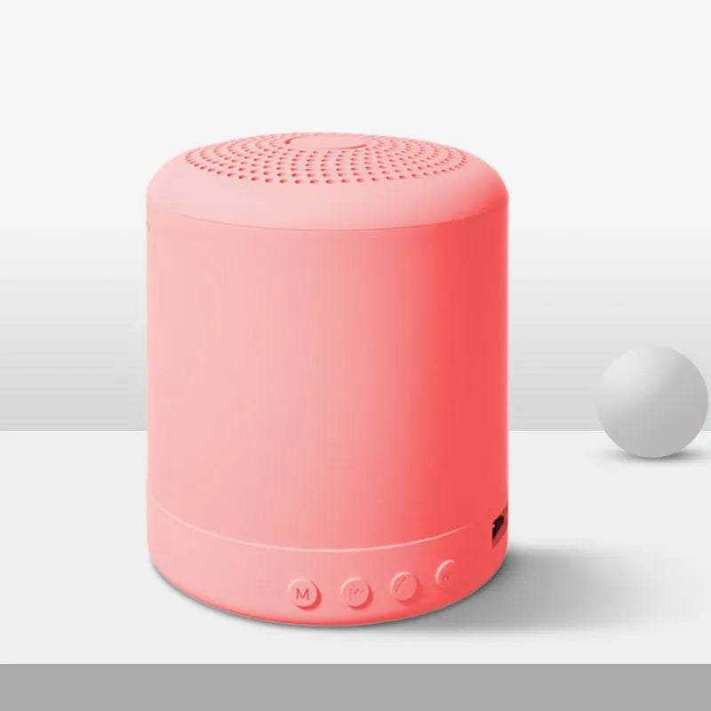 A11 compact wireless subwoofer speaker in black, pink, blue, or green colour on a desk.