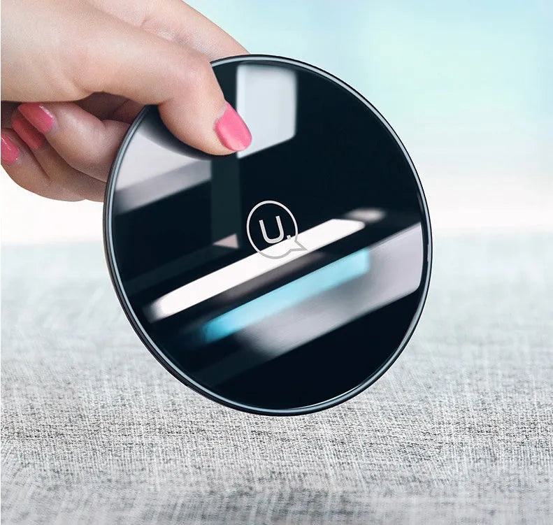 Black or white glass disc wireless charger on a surface, showing status light.